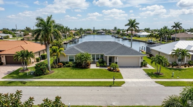 Well-maintained Cape Coral home with shingle roof on a canal-front lot in a typical Lee County Florida neighborhood