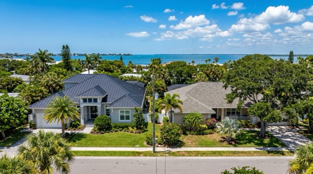 Side-by-side comparison of standing seam metal roof and shingle roof on neighboring Sarasota Florida coastal homes